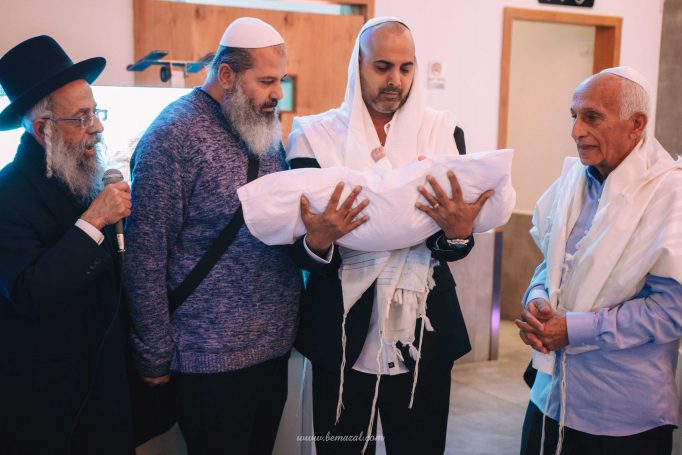 האב מחזיק התינוק לפני החיתוך